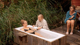Drei Frauen entspannen im Freien mit einer Badewanne in der Natur im Ferienpark RØSTIG Dorst, Nord-Brabant.