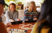 Four people enjoy playing a board game together in a cozy tent at RØSTIG Dorst holiday park, Netherlands.
