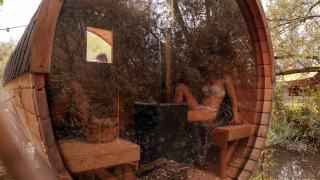 Runde Holzsauna mit Glasfront im Ferienpark RØSTIG Dorst, umgeben von Natur in Nordbrabant, Niederlande.