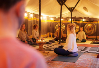 Mensen volgen een meditatie in een warme tent bij RØSTIG Dorst vakantiepark in Noord-Brabant, Nederland.
