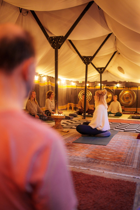 Personas meditando en una carpa acogedora del parque vacacional RØSTIG Dorst en Brabante Septentrional, Países Bajos.