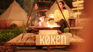 Abendliche Szene mit Lagerfeuer und Kessel bei RØSTIG Dorst Ferienpark, Nordbrabant, Niederlande.