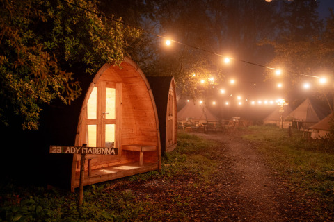 Cabaña de madera iluminada y tiendas de campaña de noche en RØSTIG Dorst, parque vacacional en Brabante Septentrional.