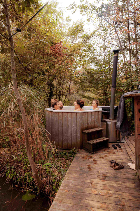 Vier mensen genieten van een buiten bubbelbad in vakantiepark RØSTIG Dorst in Noord-Brabant, Nederland.
