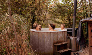 Quatre personnes se détendent dans un bain nordique en plein air au parc de vacances RØSTIG Dorst, North-Brabant.