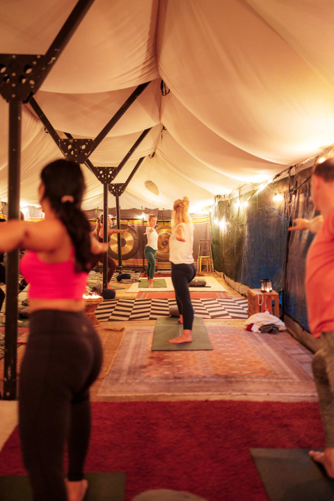 Personas participan en una clase de yoga bajo una carpa iluminada en RØSTIG Dorst, Brabante Septentrional.