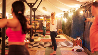 Menschen machen Yoga in einem stimmungsvoll beleuchteten Zelt im Ferienpark RØSTIG Dorst, Nordbrabant.