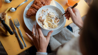 Frühstück mit Croissant, Joghurt mit Banane und Granola auf gelbem Tisch im Ferienpark RØSTIG Dorst.