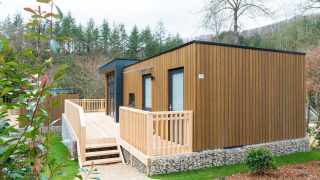 Modern wooden lodge with spacious deck surrounded by greenery at Cube La Mer holiday destination.