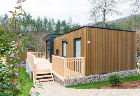 Moderna cabaña de madera con terraza amplia y entorno natural en Cube La Mer, destino vacacional.