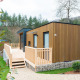 Moderne lodge med træbeklædning og stor terrasse i grønne omgivelser ved Cube La Mer feriepark.