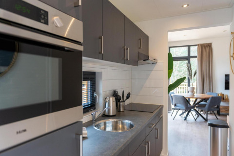 Moderne keuken en eetruimte bij Cube La Mer, Kohnenhof Luxemburg, met grijze kasten en natuurlijk licht.