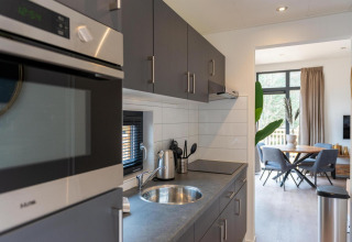 Moderne keuken en eetruimte bij Cube La Mer, Kohnenhof Luxemburg, met grijze kasten en natuurlijk licht.