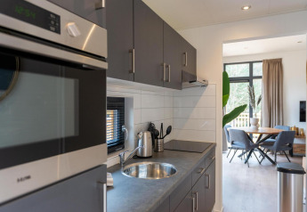 Modern kitchen and dining area at Cube La Mer, Kohnenhof Luxembourg, featuring sleek gray cabinetry and natural light.