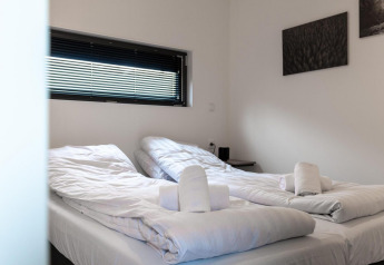 Ein modernes Doppelzimmer im Cube La Mer in Kohnenhof, Luxemburg, mit weißen Betten und Handtüchern.