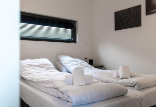 Moderne tweepersoonskamer in Cube La Mer te Kohnenhof, Luxemburg met witte bedden en opgerolde handdoeken.