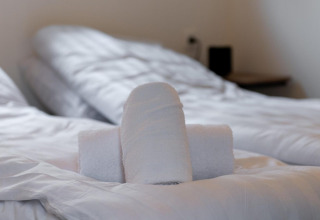 Toallas enrolladas sobre una cama en Cube La Mer en Kohnenhof, Luxemburgo, ambiente acogedor de hotel.