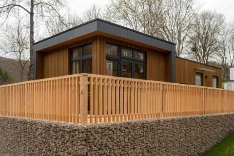 Moderne Cube La Mer lodge bij Kohnenhof in Luxemburg met houten gevel en ruime houten omheinde veranda.