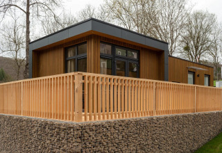 Lodge moderne Cube La Mer au Kohnenhof au Luxembourg, structure bois et terrasse spacieuse avec clôture bois.