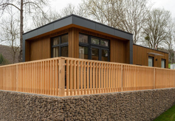 Modern Cube La Mer lodge at Kohnenhof in Luxembourg, featuring a wooden exterior and spacious fenced terrace.