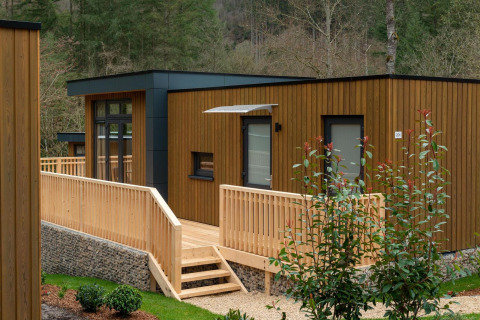 Lodge moderne en bois avec rampe et terrasse au Cube La Mer, Kohnenhof, Luxembourg, entouré de forêt.
