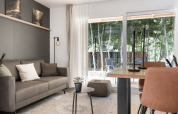 Modern living room at Domus lodge in Kohnenhof, Luxembourg, with forest view through large windows.