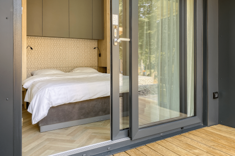 View into a bedroom with double bed, white linens, and modern design at Domus Lodge, Kohnenhof, Luxembourg.