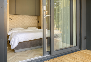 View into a bedroom with double bed, white linens, and modern design at Domus Lodge, Kohnenhof, Luxembourg.