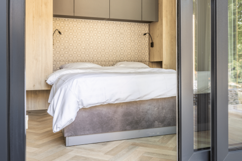 Dormitorio moderno de lodge con cama doble, detalles de madera y pared estampada en Domus en Kohnenhof, Luxemburgo.