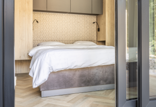 Modern lodge bedroom with double bed, wood accents, and patterned wall at Domus at Kohnenhof in Luxembourg.