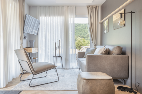 Helles, modernes Wohnzimmer in der Domus Lodge bei Kohnenhof, Luxemburg, mit Sofa und Ausblick.