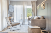 Salon lumineux et moderne à la Domus de Kohnenhof, Luxembourg, avec canapé, fauteuil et vue extérieure.