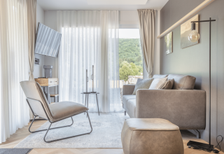 Lichte, moderne woonkamer bij Domus in Kohnenhof, Luxemburg, met bank, stoel en uitzicht op de natuur.