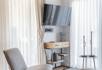 Moderne lodge-woonkamer bij Domus in Kohnenhof, Luxemburg met stoel, tv aan de muur en daglicht.