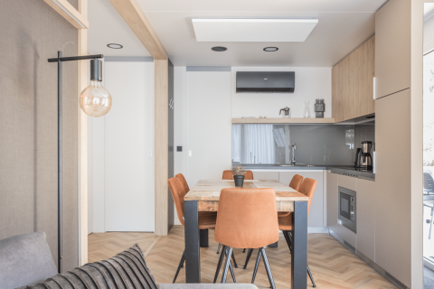 Coin repas moderne à Domus au Kohnenhof au Luxembourg, quatre chaises orange, lumière naturelle apaisante.