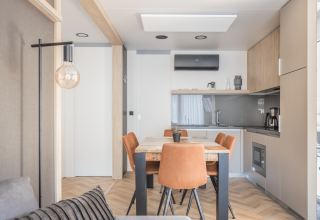 Coin repas moderne à Domus au Kohnenhof au Luxembourg, quatre chaises orange, lumière naturelle apaisante.