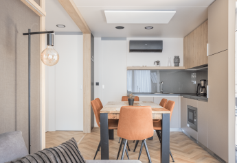 Coin repas moderne à Domus au Kohnenhof au Luxembourg, quatre chaises orange, lumière naturelle apaisante.