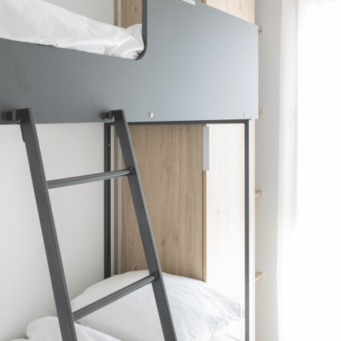 Modernes Etagenbett mit grauen und Holzelementen im Domus bei Kohnenhof in Luxemburg mit Tageslicht.