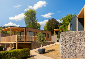 Moderne Silvanus-Lodges in Kohnenhof, Luxemburg, mit Natursteinmauern und grüner Umgebung.