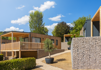 Moderne Silvanus-lodges ved Kohnenhof, Luxembourg, omgivet af sten og natur på en solrig dag.