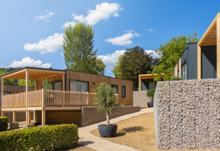 Lodges modernes Silvanus à Kohnenhof, Luxembourg, entourés de murs en pierre et de verdure.