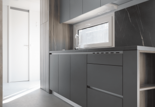 Moderne, minimalistische keuken in Silvanus lodge bij Kohnenhof in Luxemburg met grijze kasten en raam.