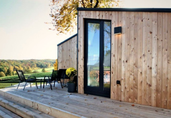 Buitenterras bij Panorama Cottage met moderne houten gevel en panoramisch uitzicht op het landschap.