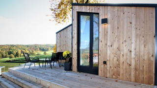 Buitenterras bij Panorama Cottage met moderne houten gevel en panoramisch uitzicht op het landschap.