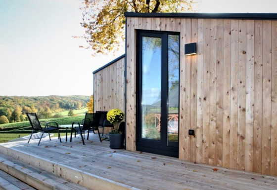 Buitenterras aan Panorama Cottage met houten gevelbekleding en prachtig zicht op het glooiende landschap.
