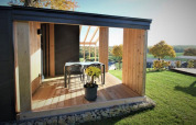 Terrazza in legno con tavolo e sedie e vista panoramica su campi al Panorama Cottage, Gulperberg, Paesi Bassi.