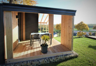 Lichte houten veranda met tafel en stoelen, uitkijkend op velden bij Panorama Cottage, Gulperberg in Nederland.