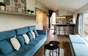 Moderne stue og køkken i Panorama Cottage på Gulperberg, Nederlandene, med blå sofaer og lyse træmøbler.