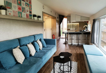 Moderne stue og køkken i Panorama Cottage på Gulperberg, Nederlandene, med blå sofaer og lyse træmøbler.