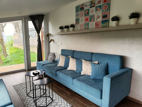 Modern living room at Panorama Cottage, Gulperberg, Netherlands, with blue sofa and large glass doors.